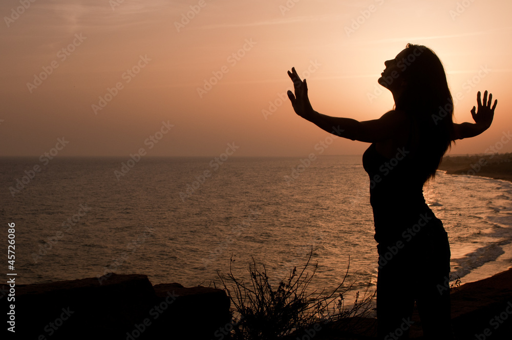 Silhouette of young woman on a hill by the sea