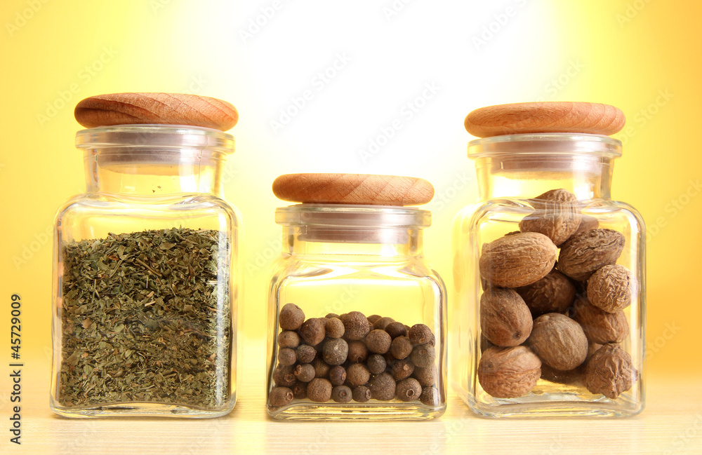 powder spices in glass jars on yellow background powder spices in glass jars on yellow background