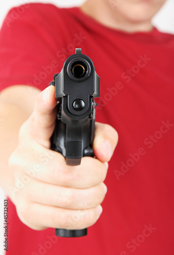 Teenager with a gun in his hand, focus on the gun