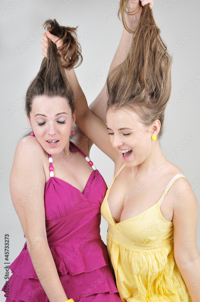 Two funny girl friends pull each other hair. Stock Photo | Adobe Stock