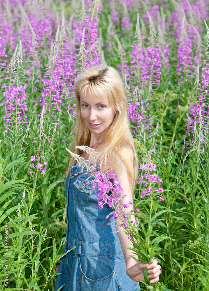 The smiling young woman with bunch of willowherb flower The smiling young woman with bunch of willowherb flower