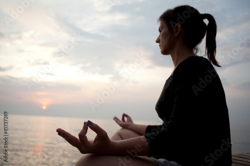 young woman meditating by the sea