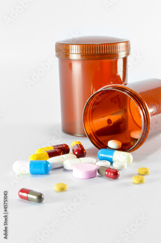 Pills pouring out of the brown bottle on isolated background