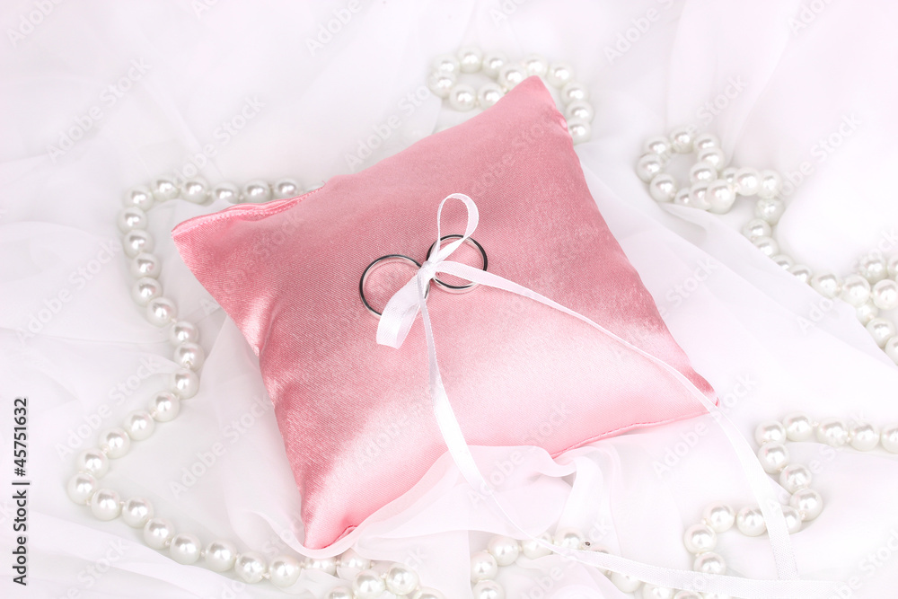 Wedding rings on satin pillow on white cloth background Wedding rings on satin pillow on white cloth background
