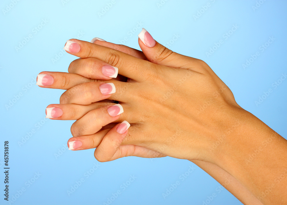 Beautiful woman's hands with french manicure on blue background