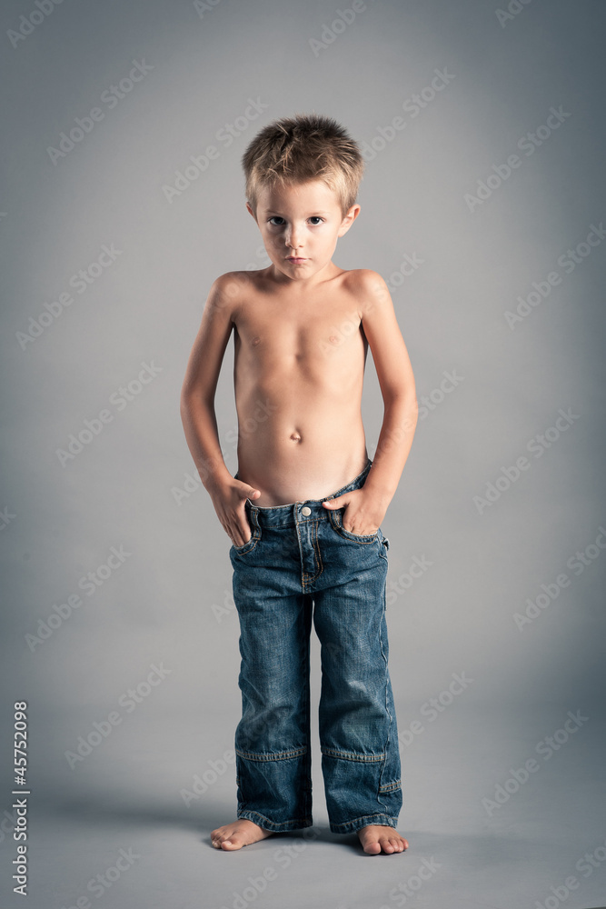 Young boy posing. Studio portrait with grey background.