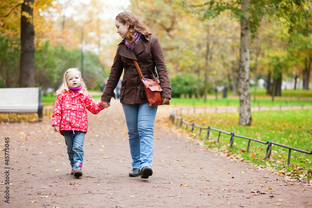 Mother and daughter walking in autumn park together Mother and daughter walking in autumn park together