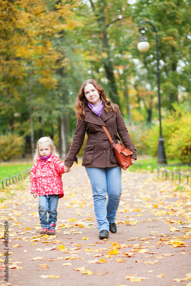 Beautiful mother and daughter walking in autumn park together Beautiful mother and daughter walking in autumn park together