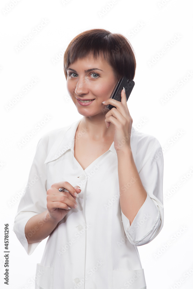 Молодая девушка в белом халате беседует по мобильному телефону