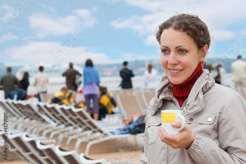 Canvas Print Young girl holding cup on deck of big passenger ship