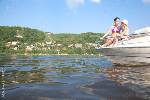 Mother daughter sunbathing on cutter on river