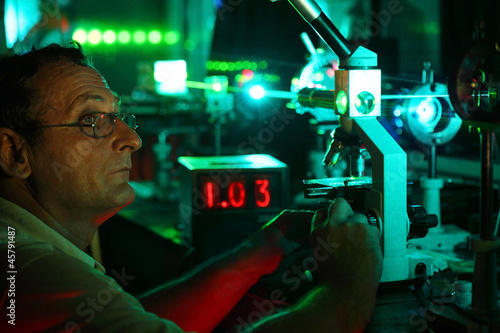 Scientist with glass demonstrate laser of microparticles photo