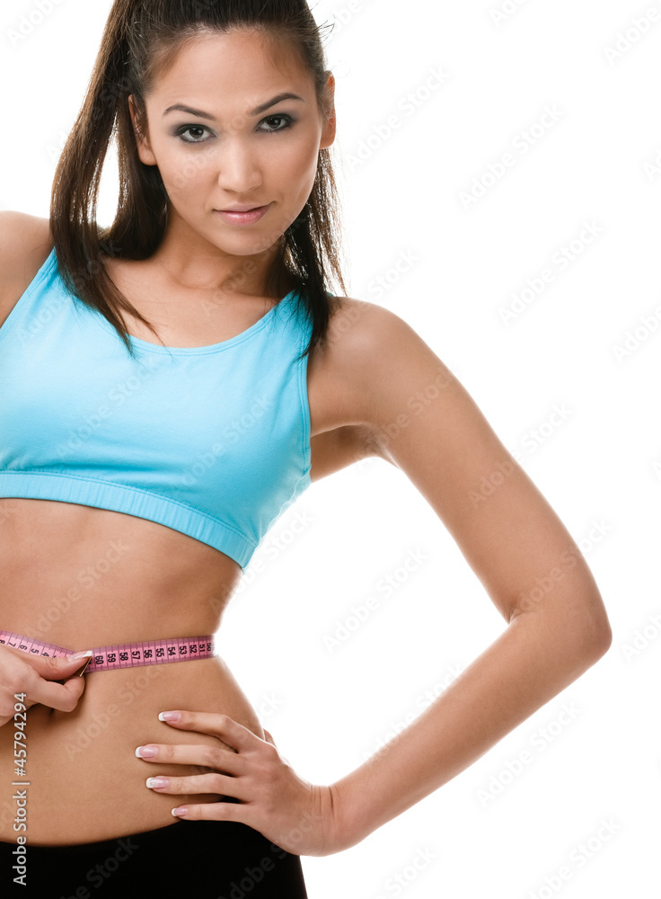 Fototapeta premium Sporty woman measures her waist with measuring tape