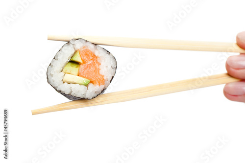 Fingers holding maki sushi roll with chopsticks