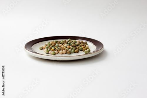 snow pea seeds on plate against white background