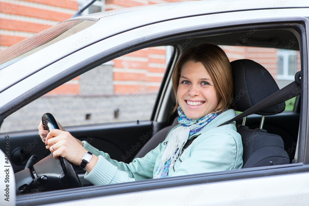 Happy blond woman holding steering wheel in new car Happy blond woman holding steering wheel in new car