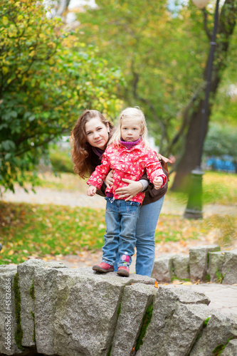 Outdoor portrait of beautiful mother and daughter on a little br