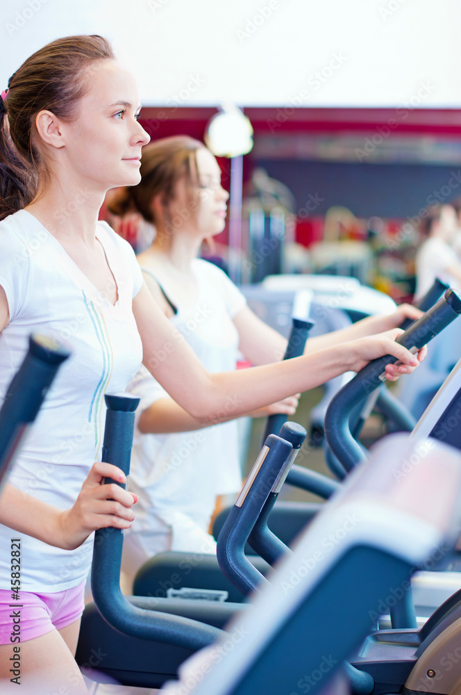 Two young sporty women run on machine Two young sporty women run on machine