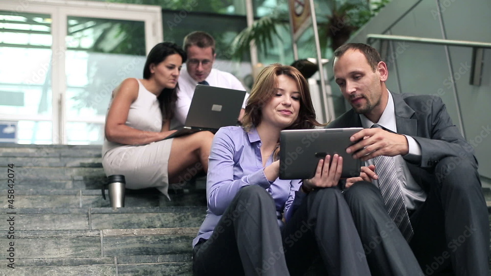 Young business people with tablet computer on stairs by office b Young business people with tablet computer on stairs by office b