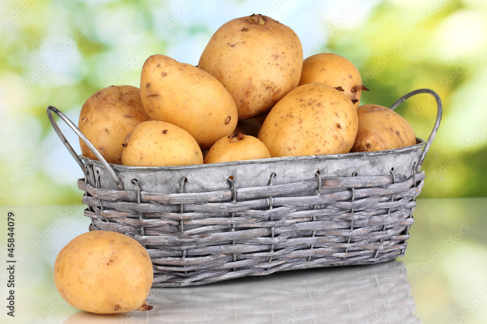 Ripe potatoes on basket on table on natural background Ripe potatoes on basket on table on natural background