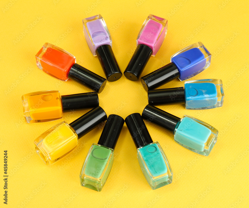 Group of bright nail polishes, on yellow background
