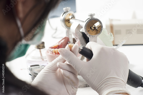 Dental technician working with articulator photo