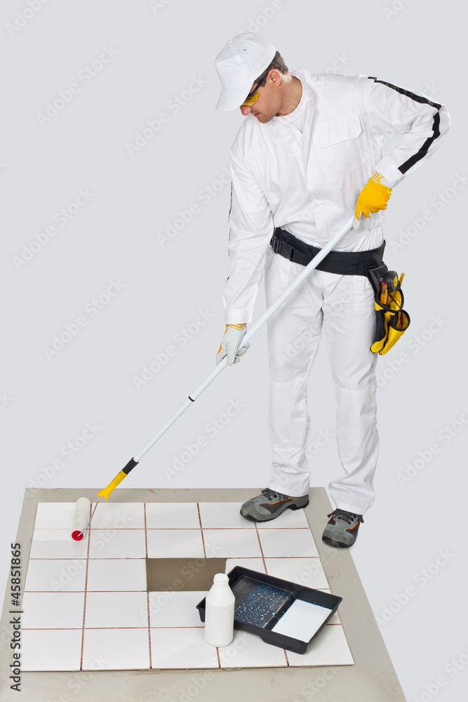 Fototapeta premium worker paint with primer old tiles floor with roller