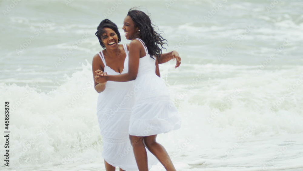 Diverse parent and daughter gossiping and walking by ocean Diverse parent and daughter gossiping and walking by ocean