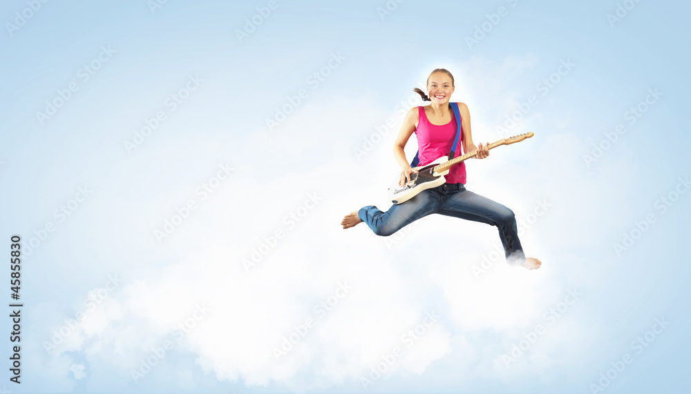 young woman playing on electro guitar and jumping