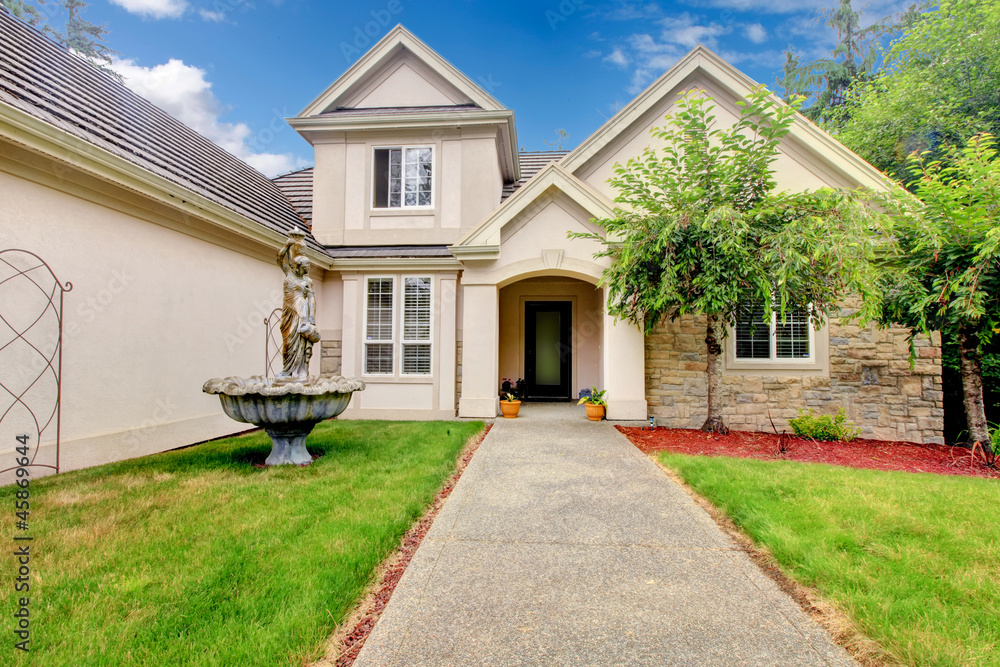 Large beautiful beige and grey house exterior during summer.