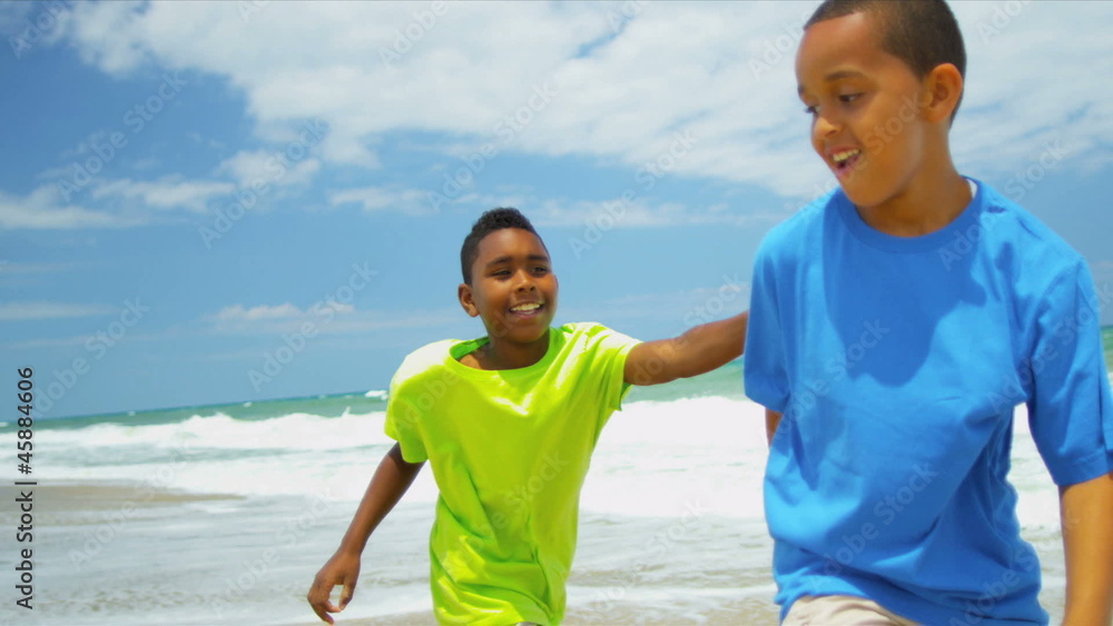 Two diverse boys playing and laughing together on beach 