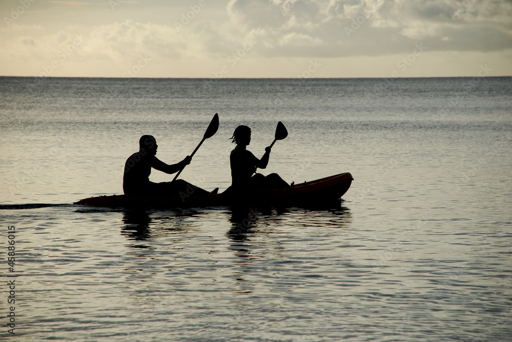 Man and woman silhouetted at sea in a kayak