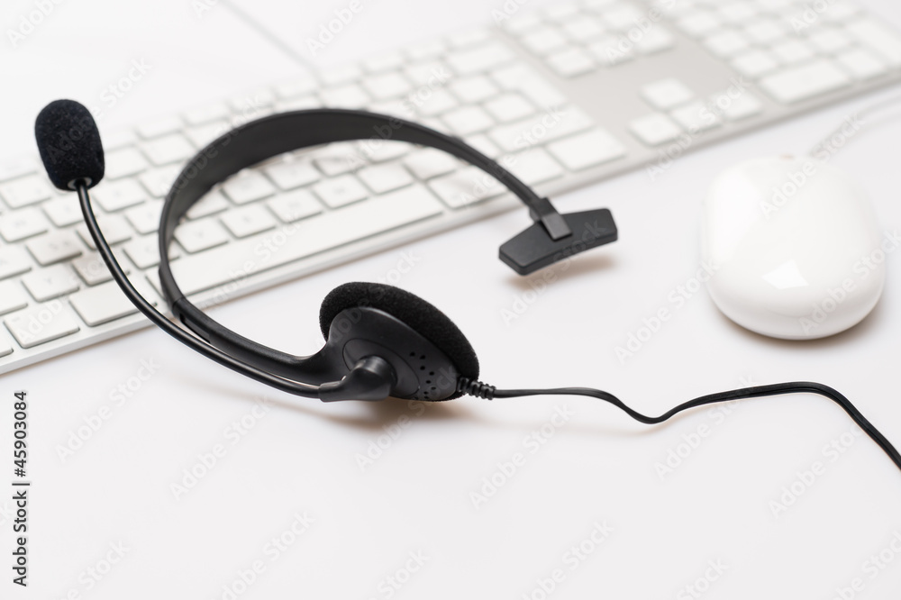 Office black headphones on white keyboard Office black headphones on white keyboard