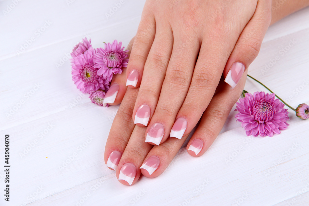 Fototapeta premium Woman hands with french manicure and flowers