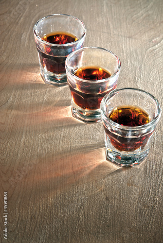 Three shot glasses full of dark colored alcohol