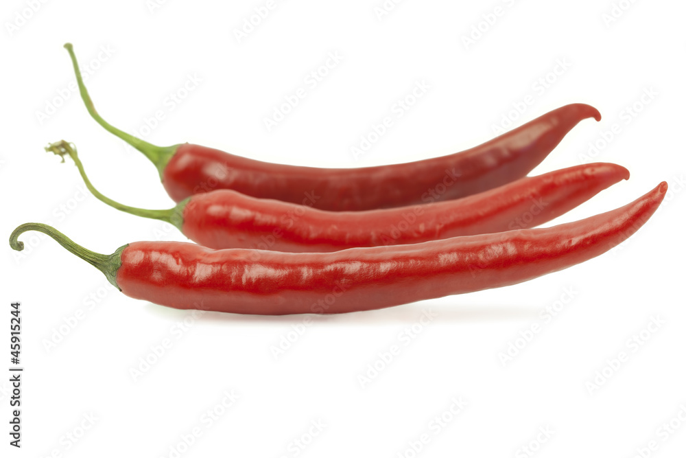 Three red chili peppers in row on white background