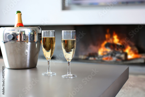 Fototapeta Closeup of champaign glasses set by fireplace