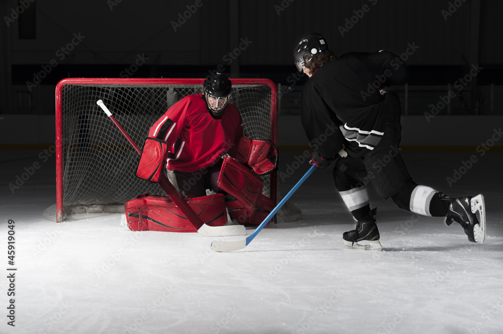 Fototapeta premium Ice hockey goalie with skaters shooting puck