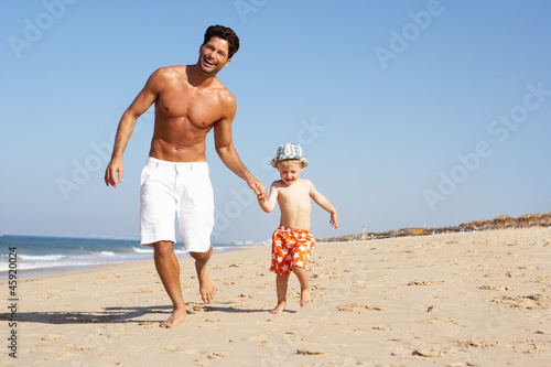 Father And Son Running Along Beach
