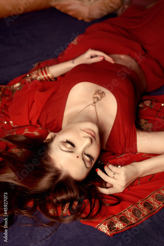 beautiful indian woman laying in ethnic interior