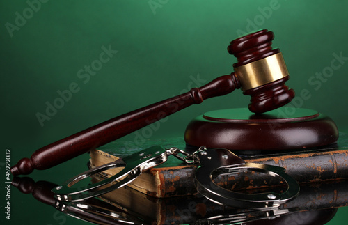 Gavel, handcuffs and.book on law on green background