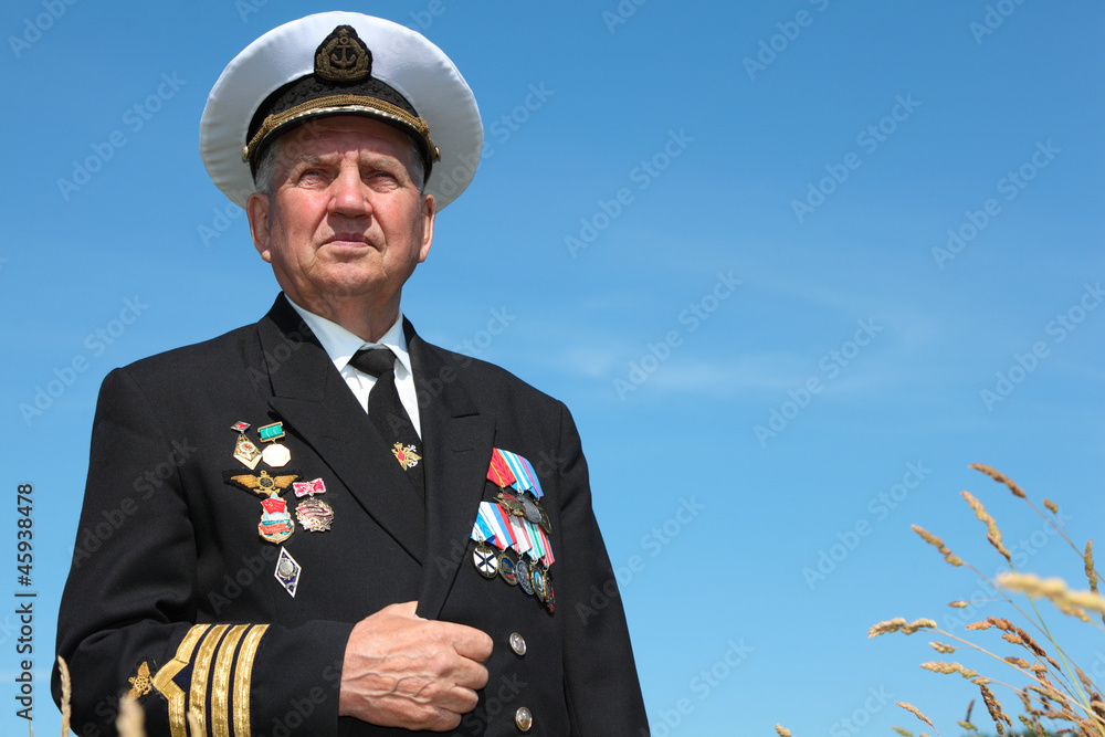 Grandfather in form, cap, ordens, medals pose background sky Grandfather in form, cap, ordens, medals pose background sky