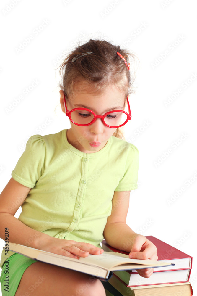 Little girl seat, hold, read book, pose face near stack of books Little girl seat, hold, read book, pose face near stack of books