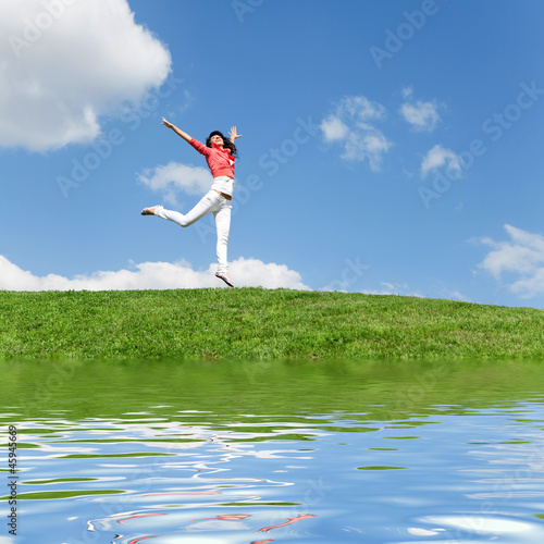 pretty young woman jumping on green grass