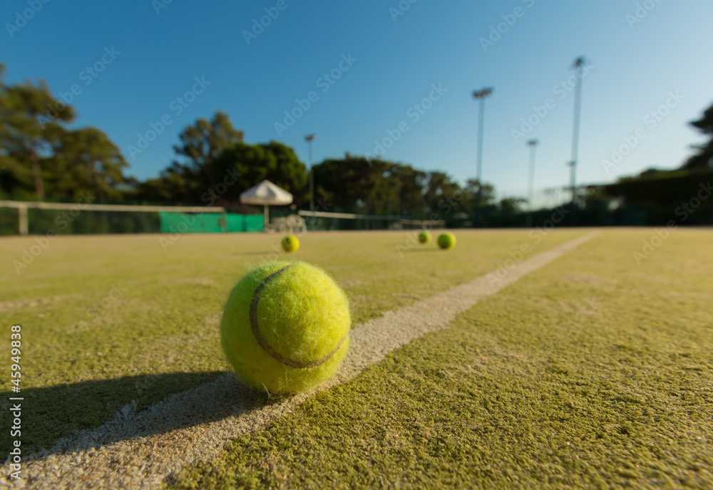 Tennis ball on a line of a green tennis court