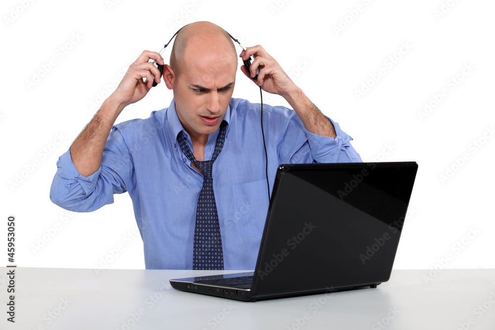 Bald businessman with laptop and headphones Bald businessman with laptop and headphones