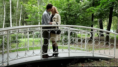 Двое влюблённых целуются на мостике