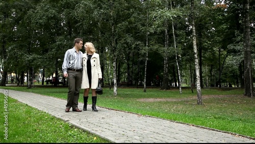 Двое влюблённых идут по дорожке парка
