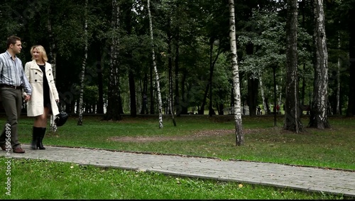 Двое влюблённых идут по дорожке парка