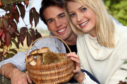 Bild auf Leinwand Couple collecting chestnuts and mushrooms in the forest